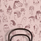 A repeating pattern of hand-drawn caricature faces in dark brown ink on a dusty pink background.