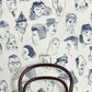 A repeat pattern of hand-drawn caricature faces in dark blue ink on a warm off-white textured background.
