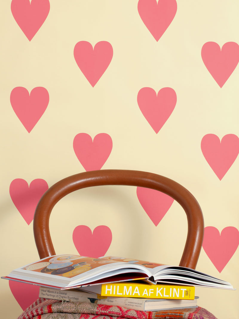 Hand screen printed wallpaper featuring pink hearts on a pale yellow background.